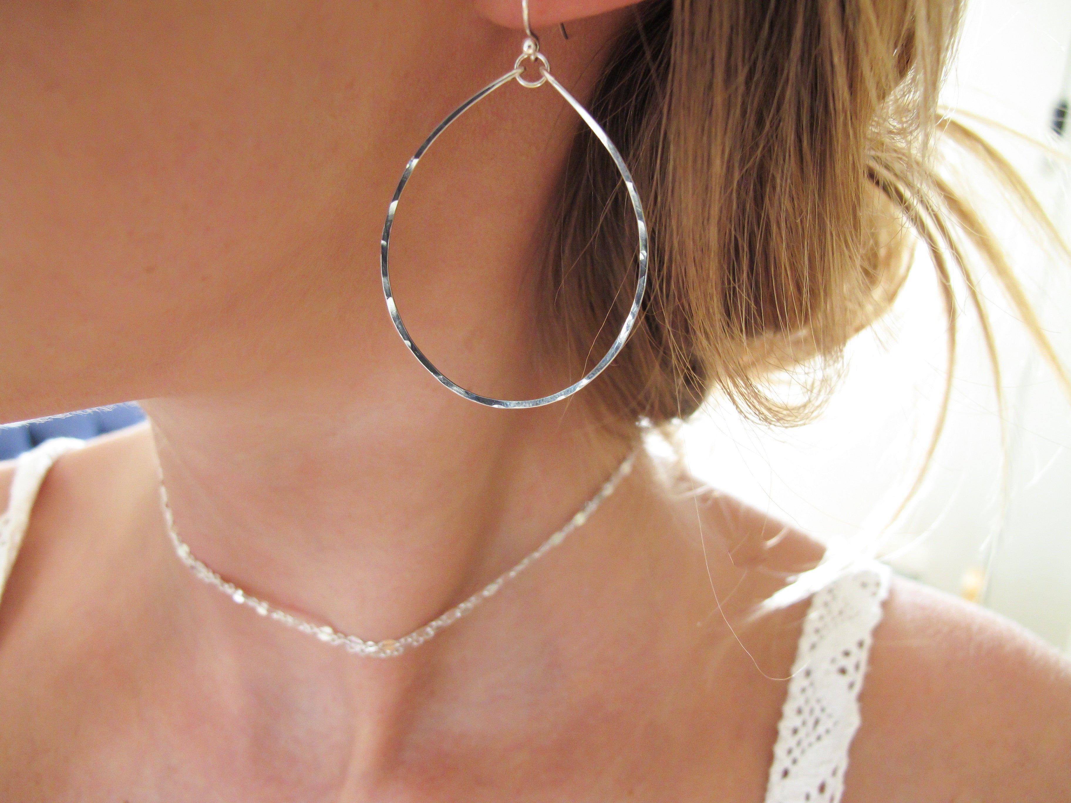 blond woman on a white top ear closeup wearing sterling silver hoops for nuns hoop earrings