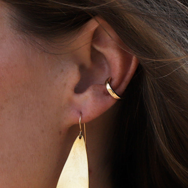 Woman wearing a Gold Hugh Hoop and drop-shaped gold earring closeup