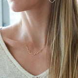 blond woman on a white v neck wearing a 14k gold filled im hammered necklace