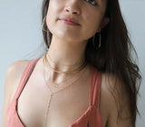 brunette on a pink top wearing a 14k gold filled tied up choker wrap necklace