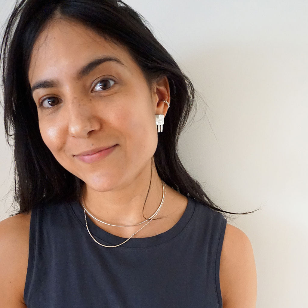 brunette wearing sterling silver jellyfish post earrings and sterling silver stacked cartilage hoop earrings 