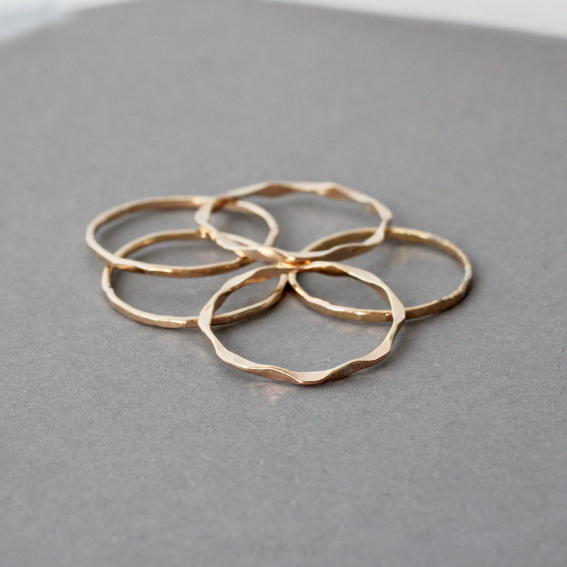 mixed set of 14k gold filled wavy and flat rings laying on a grey surface