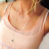 girl with layered long and short silver necklaces and 2 silver circles fused together into an infinity symbol