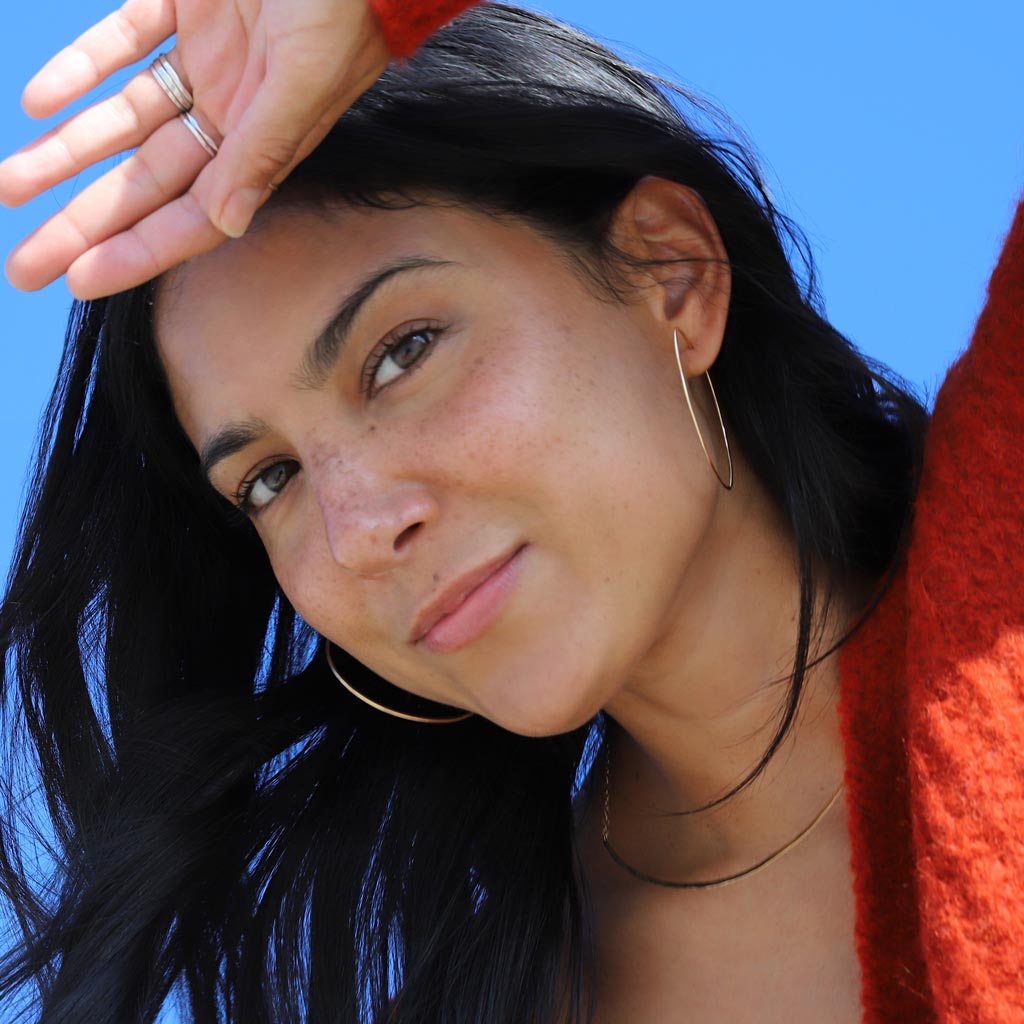 girl with thin gold hoops and orange sweater