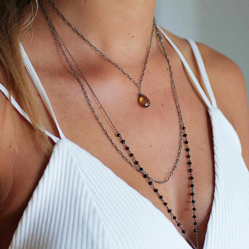 blond woman cleavage wearing an oxidized sterling silver long y black spinel gemstone necklace