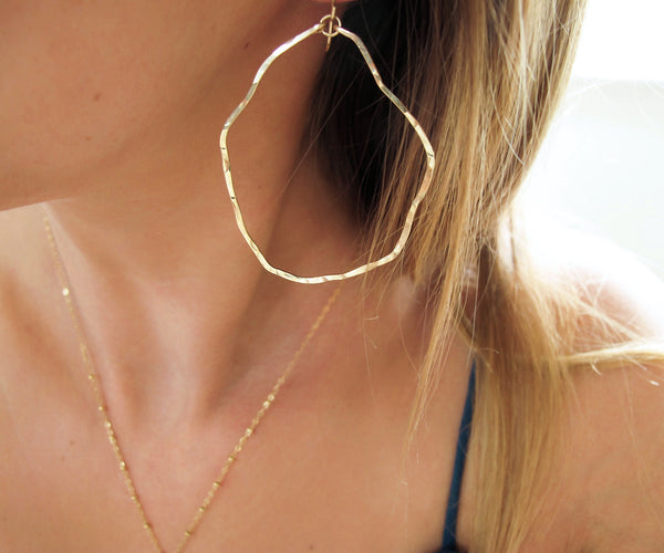 closeup of gold wavy irregular hoop earrings hand hammered and handmade by delia langan jewelry