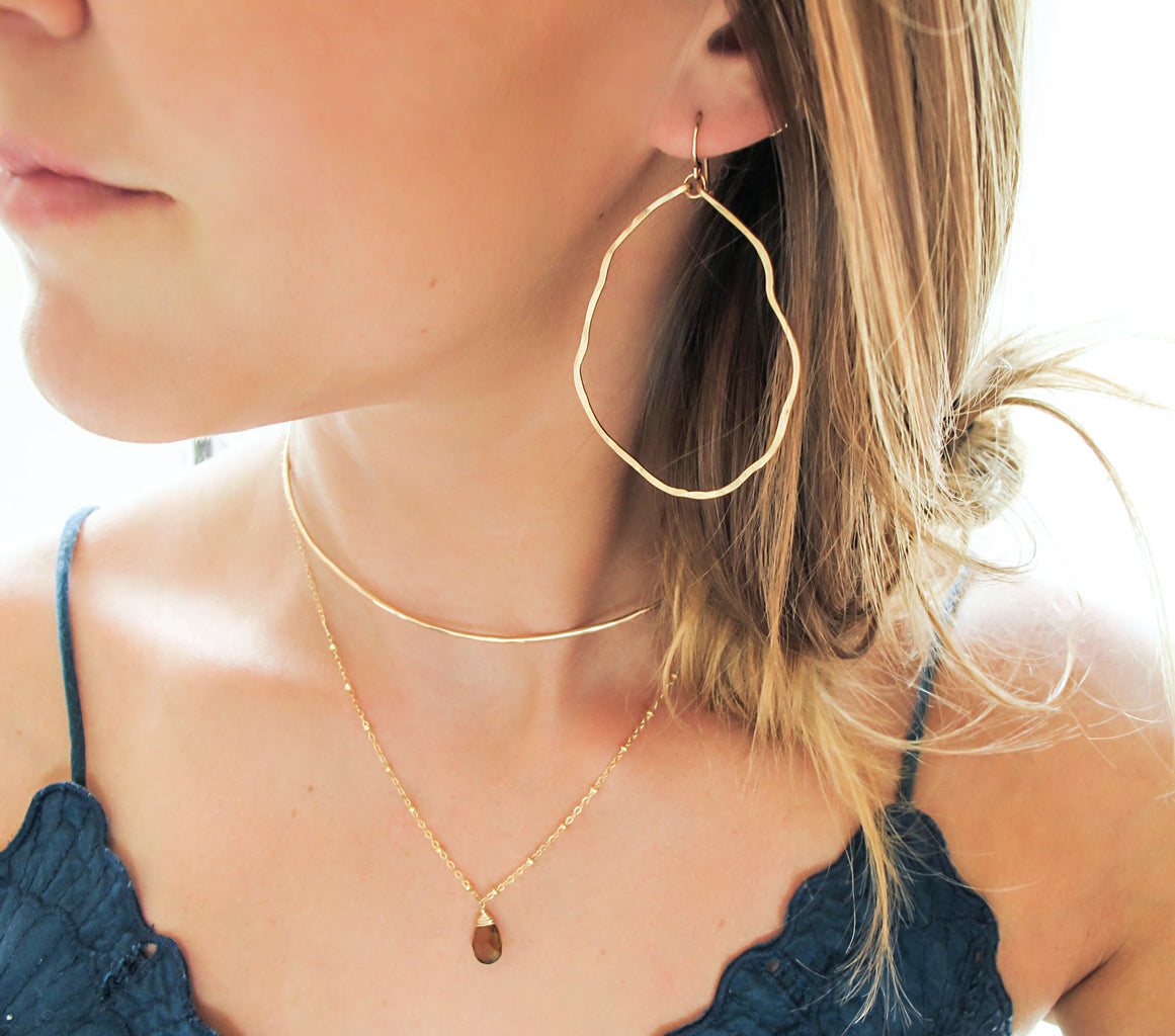blond woman on a dark green top wearing 14k gold filled potatohead hoop earrings