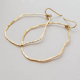 side view of gold wavy irregular hoop earrings hand hammered and handmade by delia langan jewelry