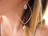 blond woman on a blue top ear closeup wearing rose quartz rose gold leaf gemstone earrings partially reflecting light