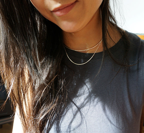 brunette on a navy blue tshirt wearing a sterling silver scenic route necklace partially under sunlight