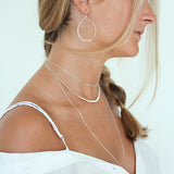girl with delicate silver layering necklaces and silver oval hoops