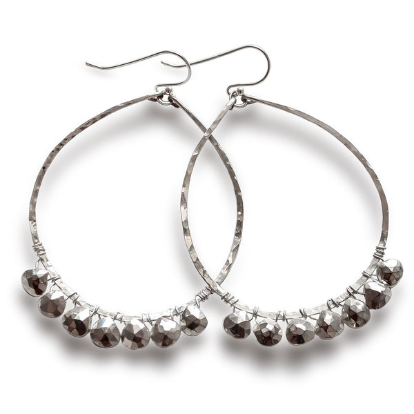 sterling silver silver metallic party girl hoops on a white surface partially under a bright light