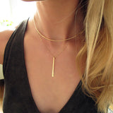 blond woman on a black top wearing a 14k gold filled single stroke necklace