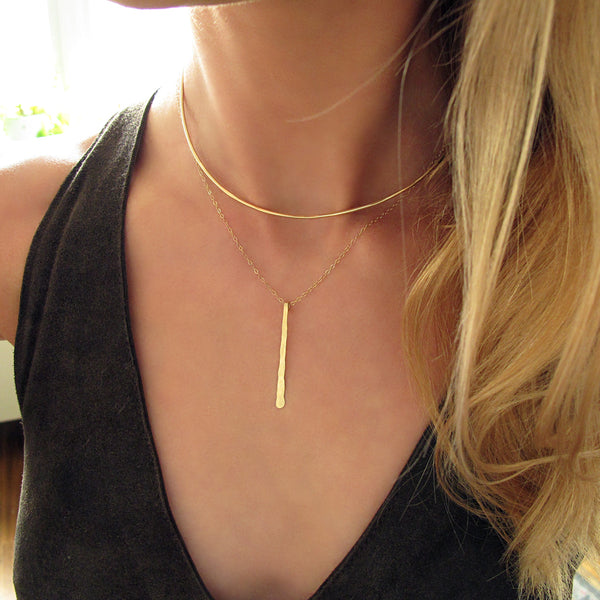 blond woman on a black top wearing a 14k gold filled single stroke necklace