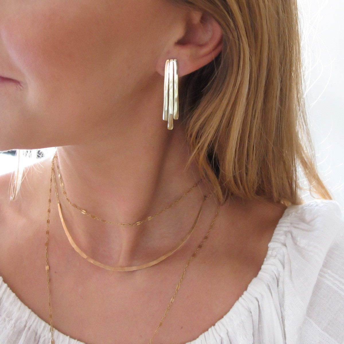 blond woman neck closeup wearing gold brass small fringe post earrings 