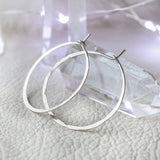 small silver endless hoop earrings leaning against a crystal