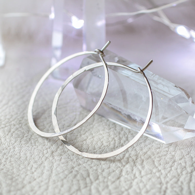 small silver endless hoop earrings leaning against a crystal