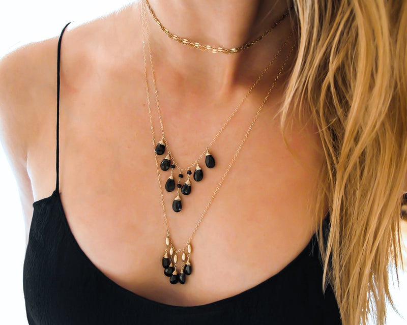 blond woman cleavage wearing two 14k gold filled black spinel cascade gemstone necklaces on different sizes