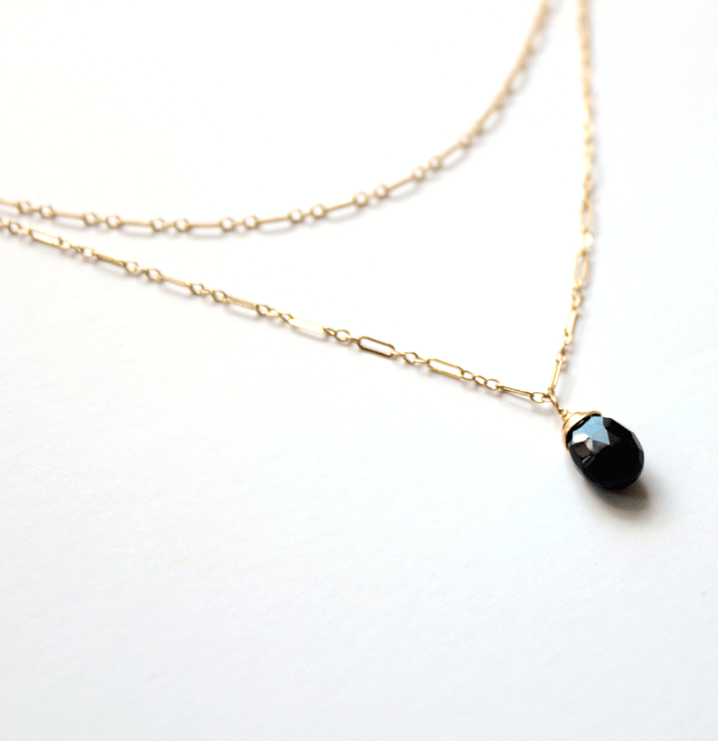 14k gold filled black spinel choker wrap gemstone necklace on a white surface under a partially bright light 