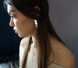 side shot of brunette wearing sterling silver three square post earrings halo collar and tied up choker necklace
