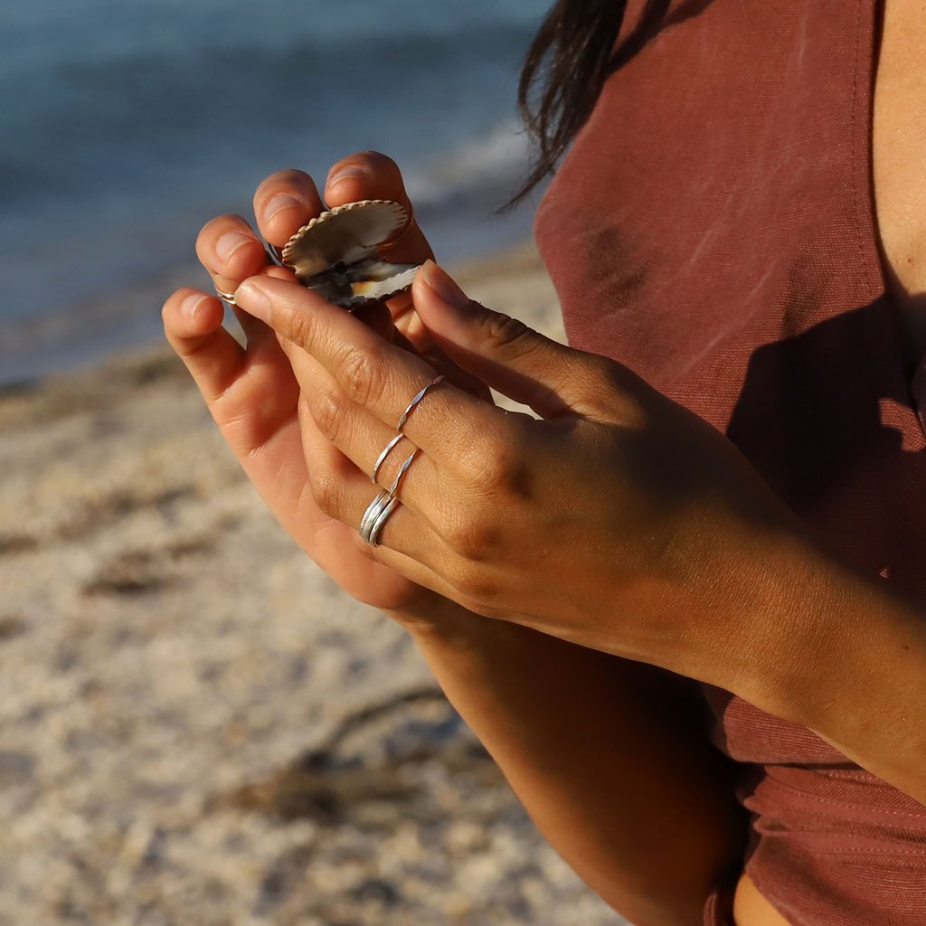 hand with silver rings holding scallop shell