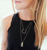 blond woman on a black tank wearing a 14k gold filled xl different strokes fringe pendant