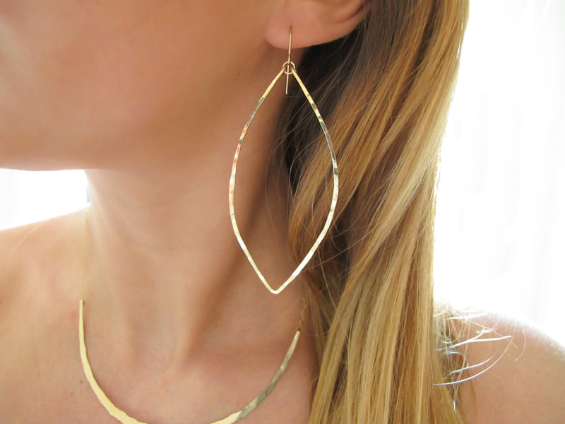 blond woman neck closeup wearing 14k gold filled xl leaf hoop earrings and 14k gold filled crescent collar necklace 